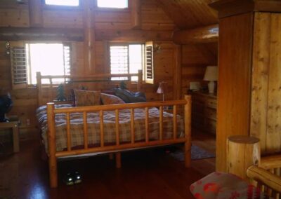 Cozy wooden cabin interior with a bed and natural light streaming in through the windows.