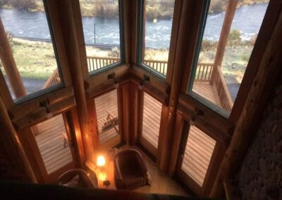 A cozy riverfront cabin interior at dusk, viewed from an upper-level loft.