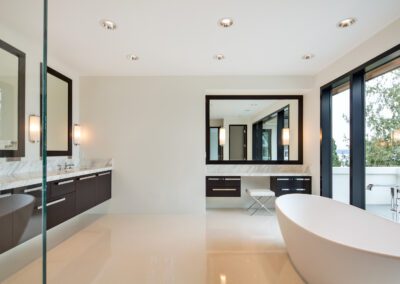 Modern bathroom with a freestanding tub, dual vanity, and large mirrors.