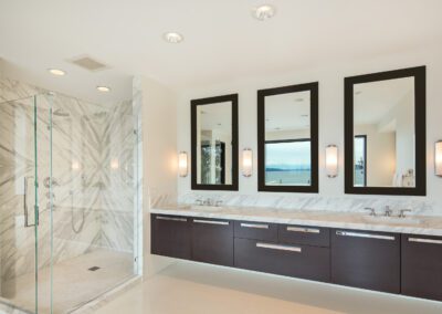 Modern bathroom with double vanity and glass-enclosed shower.